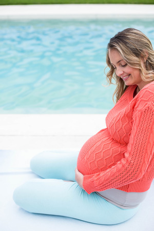 Pregnant woman relaxing outside next to the pool