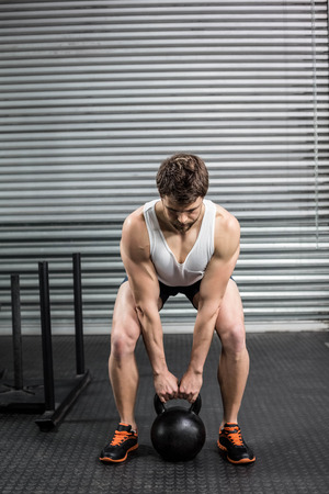 Fit man lifting dumbbells at crossfit gymの写真素材