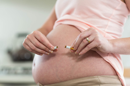 Pregnant woman destroying cigarette at home