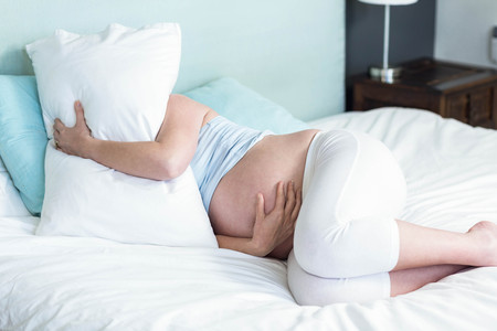Pregnant woman lying on bed at homeの写真素材
