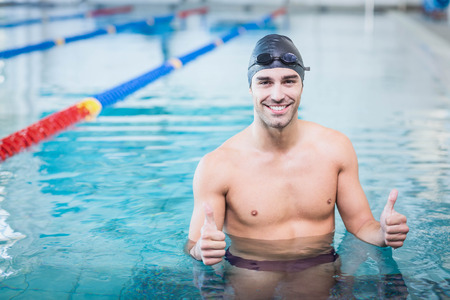 Handsome man with thumbs up in the water at the pool