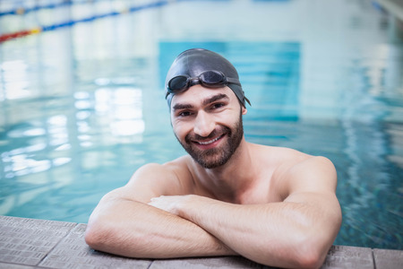 Smiling man wearing swim cap and goggles at the poolの写真素材