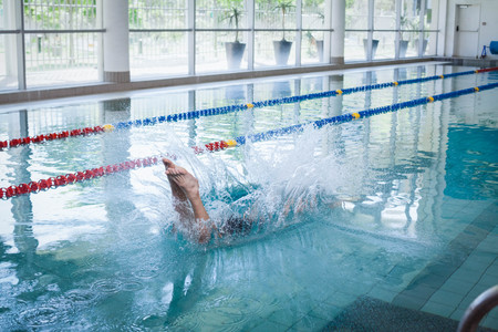 Fit man diving in the water at the pool