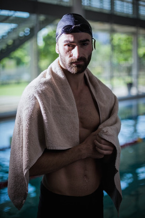 Serious man drying himself with a towel at the poolの写真素材