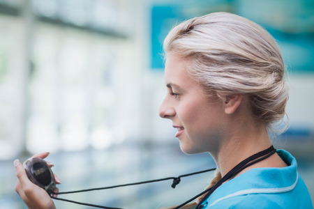 Pretty trainer looking at stopwatch at the poolの写真素材