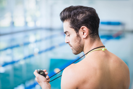 Handsome man holding stopwatch at the poolの写真素材