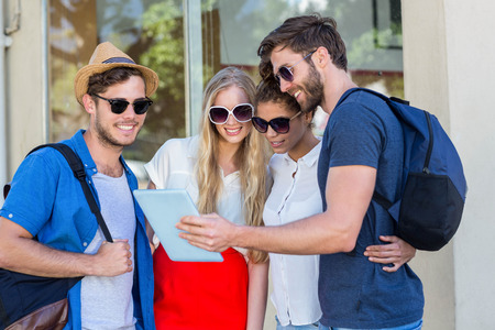 Hip friends looking at tablet in the cityの写真素材