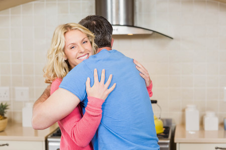 Happy couple hugging in the kitchenの写真素材