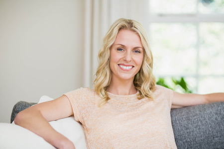 Pretty woman sitting on her couch in the living roomの写真素材