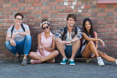 Hip friends sitting on the floor against wall on the streetの写真素材
