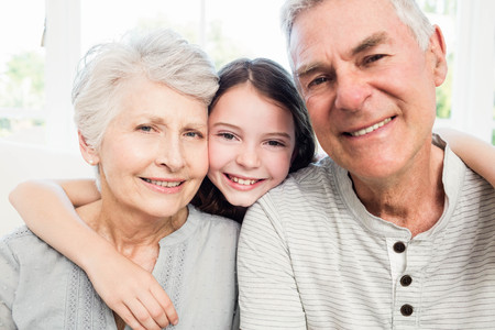 Portrait of smiling grandparents and granddaughter on the sofa