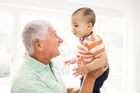 Senior man playing with his grandson at homeの写真素材