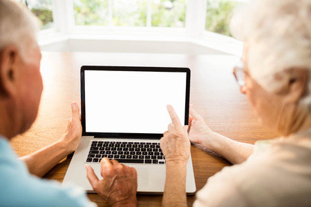 Rear view of senior couple using laptop at homeの写真素材