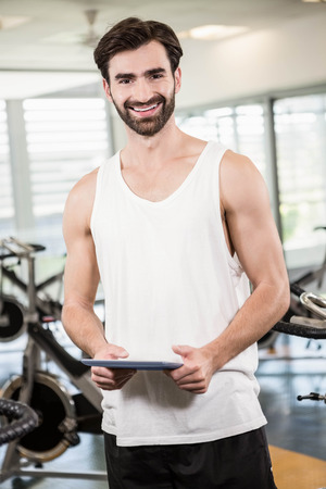 Smiling man holding tablet in the gymの写真素材