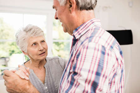 Senior couple dancing at home in the living roomの写真素材