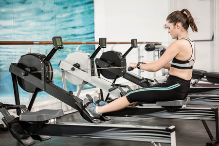Fit brunette on drawing machine at the gym