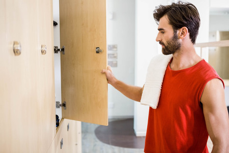 Smiling man opening locker in the gym