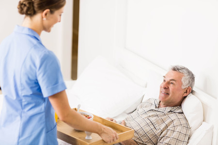 Nurse taking care of suffering senior patient at homeの写真素材