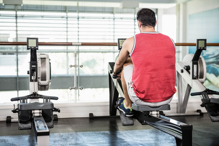 Muscular man on rowing machine at the gym