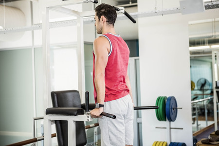 Muscular man doing pull up in a gym