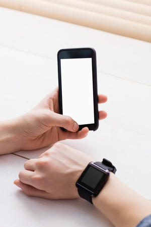 Casual businessman using phone and smart watch at her deskの写真素材