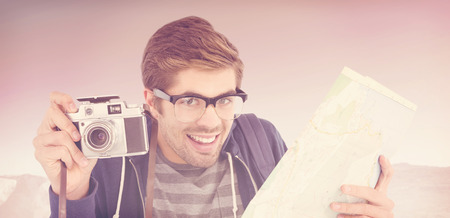 Portrait of happy man holding map and camera against mountain trailの写真素材