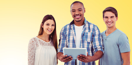 Young creative team looking at tablet against yellow background