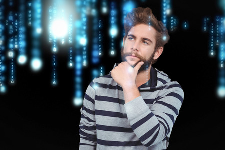 Thoughtful hipster with hand on chin against blue lines blurred letters fallingの写真素材