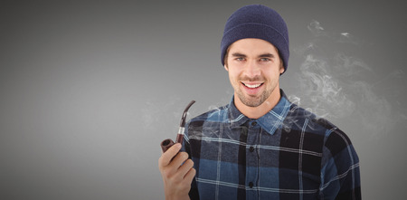 Portrait of hipster holding smoking pipe against grey vignetteの写真素材