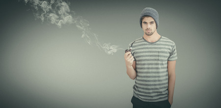 Portrait of man holding smoking pipe against grey vignette