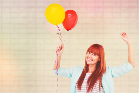 Smiling hipster woman holding balloons against textured backgroundの写真素材