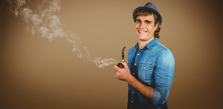 Cheerful hipster holding pipe against grey background with vignetteの写真素材
