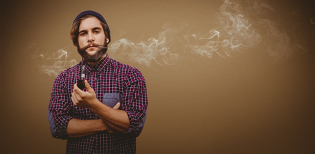 Portrait of confident hipster holding smoking pipe against grey background with vignetteの写真素材