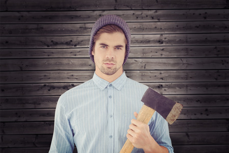 Portrait of serious hipster holding axe against wooden backgroundの写真素材