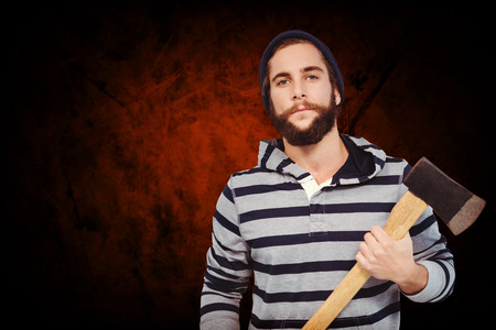 Portrait of confident hipster with hooded shirt holding axe against shades of brown