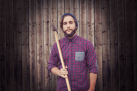 Portrait of hipster holding axe against wooden backgroundの写真素材