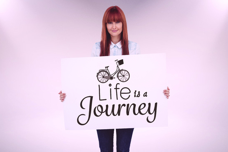 Attractive hipster woman holding white card against grey backgroundの写真素材