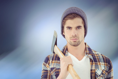 Portrait of serious hipster holding axe against cloudy skyの写真素材