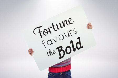 Hipster woman behind a big white card against grey backgroundの写真素材