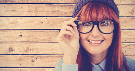 Smiling hipster woman looking at camera against wooden planks backgroundの写真素材