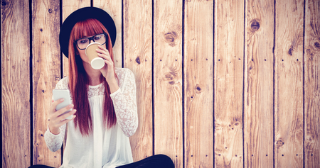 Smiling hipster woman using her smartphone against wooden planks backgroundの写真素材