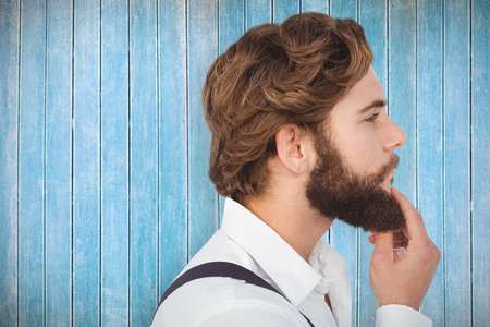 Profile view of hipster touching beard against wooden planksの写真素材