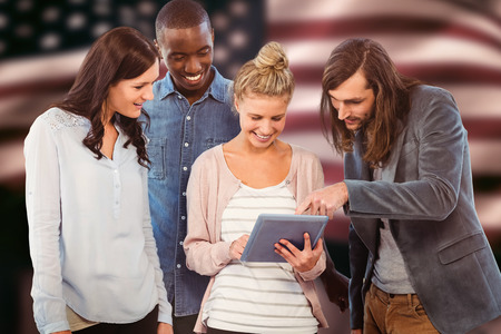 Happy woman holding digital tablet and discussing with coworkersagainst composite image of digitally generated united states national flagの写真素材