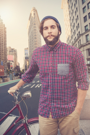 Portrait of confident hipster with bicycle against new york streetの写真素材