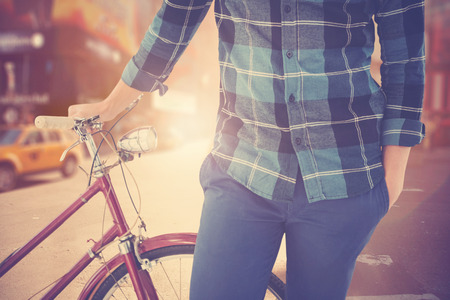 Mid section of hipster with bicycle against blurry new york streetの写真素材