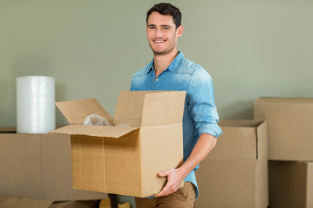 Young man carrying carton boxes in his new house
