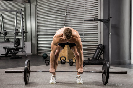 Shirtless man lifting barbell at the crossfit gymの写真素材