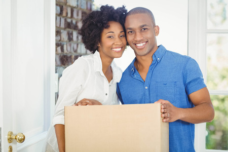 Happy couple holding box out of their houseの写真素材