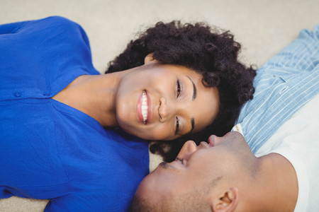 Peaceful couple lying on the floor face to faceの写真素材