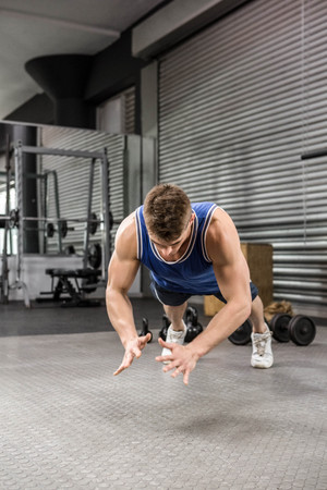 Muscular man doing push up at the crossfit gym
